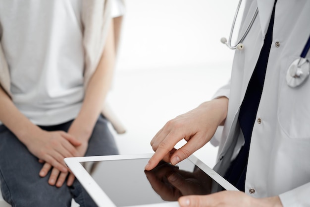 Médico e paciente infantil. O médico está usando computador tablet e está pronto para examinar o menino. O conceito de saúde ideal na medicina