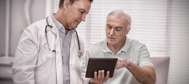 Médico e paciente sênior usando tablet digital