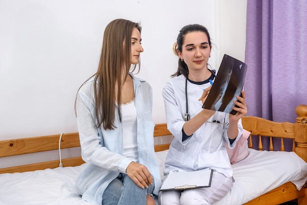 Médico e paciente sentado no sofá do hospital. Médico explicando à paciente sua radiografia do pé