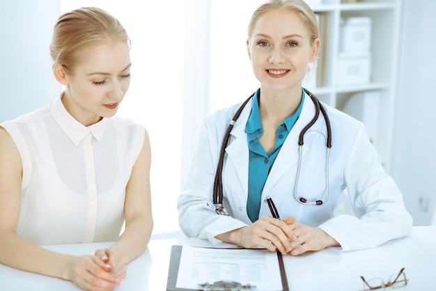 Médico e paciente sentados à mesa. O médico ou terapeuta faz um diagnóstico. Cuidados de saúde, medicina e conceito de serviço ao paciente.