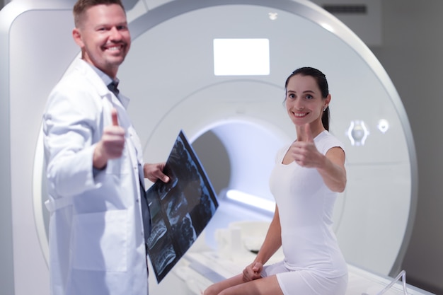 Foto médico e paciente sorridente segurando o polegar para cima no escritório para exame médico de ressonância magnética