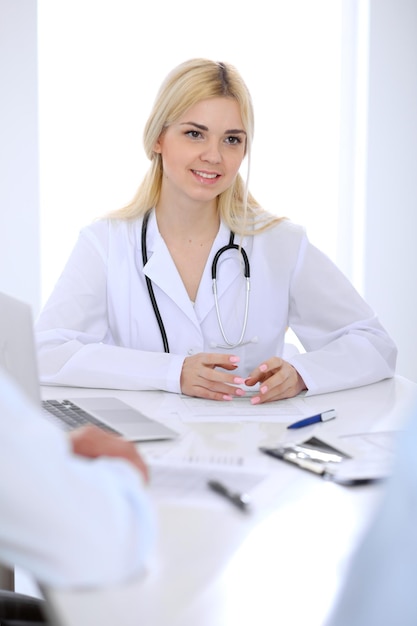 Médico e pacientes jovens casal discutindo algo na mesa. Close de mãos.