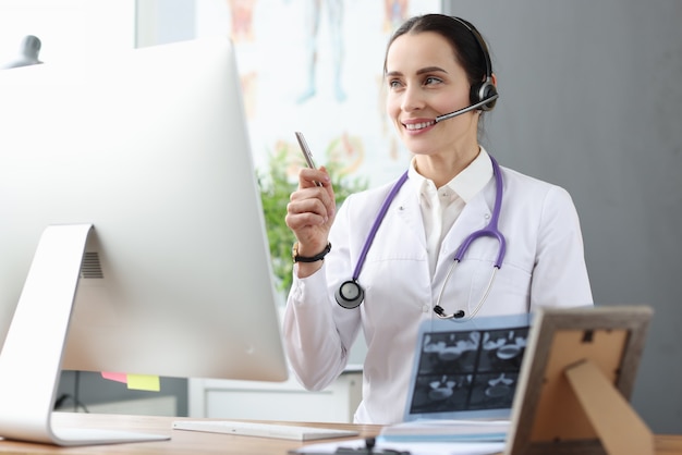 Médico em fones de ouvido, comunicando-se com o paciente por meio de um link de vídeo. Conceito de consultas médicas online