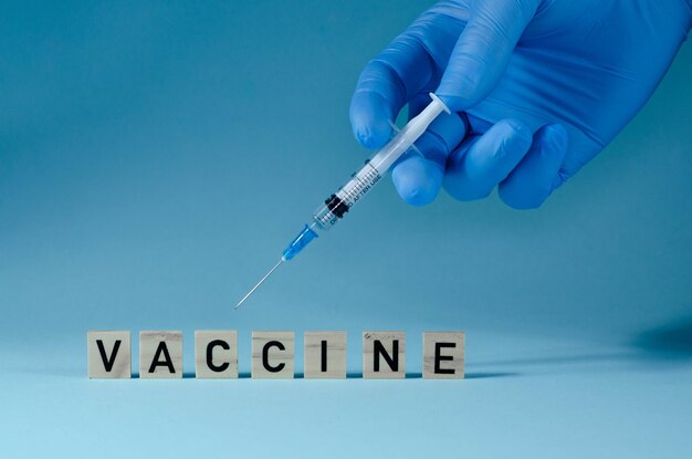Médico em luvas de látex azuis preenche seringa com remédio de frasco de vidro, closeup. Fazendo uma vacina