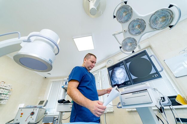 Médico em pé na sala de cirurgia com imagens de raio-x no fundo. Retrato médico masculino. Conceito médico. Foto horizontal. Veja de baixo.