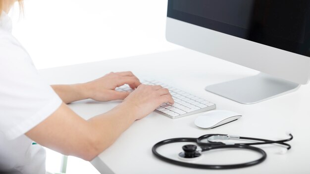 Médico em sua mesa digitando no computador