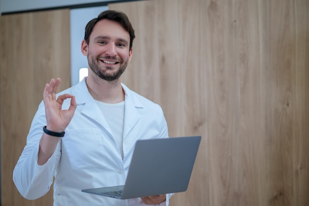 Médico em um jaleco com um laptop tendo uma sessão online