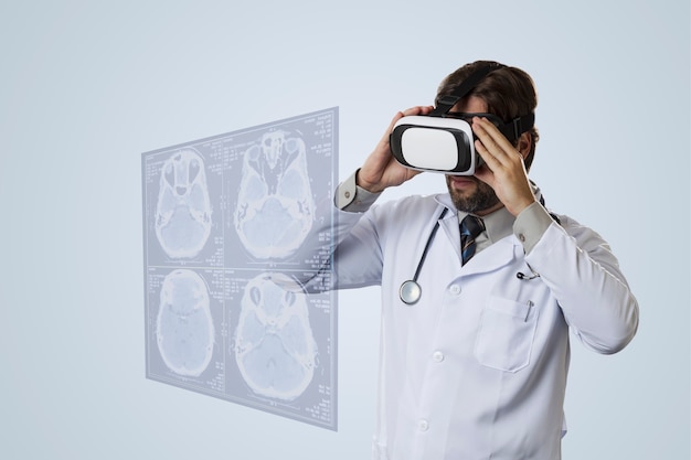 Médico em uma parede cinza, usando óculos de realidade virtual, olhando para uma tela virtual