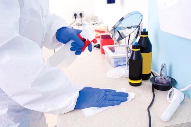 Médico em uniforme de traje de proteção limpa o laboratório.