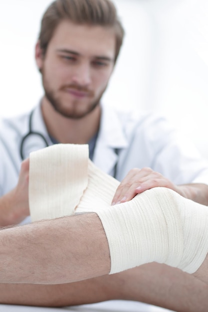 Médico enfaixando uma ferida na perna do pacienteo conceito de assistência médica