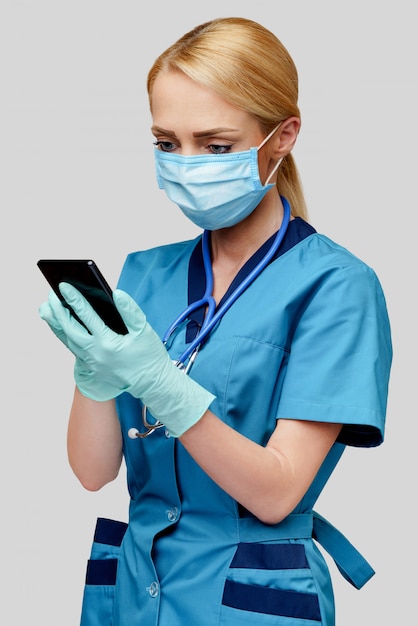 Médico enfermeira mulher com estetoscópio usando máscara protetora e luvas de borracha ou látex segurando o celular móvel