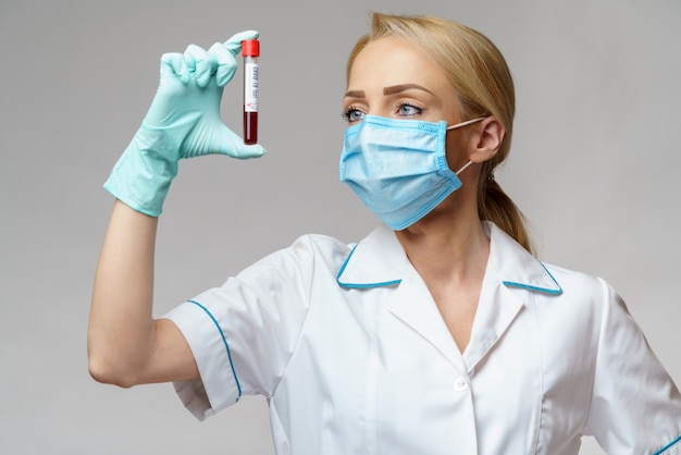 Médico enfermeira mulher vestindo luvas e máscara protetora - segurando o exame de sangue do vírus