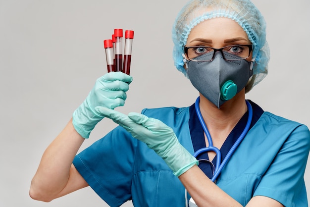 Médico enfermeira mulher vestindo luvas e máscara protetora - segurando o tubo de análise de sangue de vírus
