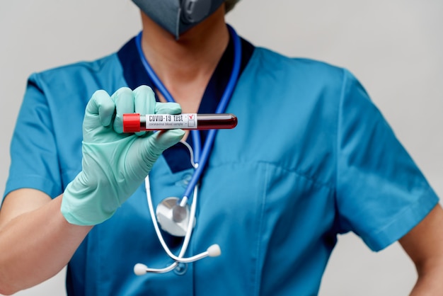Médico enfermeira mulher vestindo luvas e máscara protetora - segurando o tubo de análise de sangue de vírus