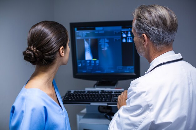 Médico y enfermera examinando rayos x en computadora