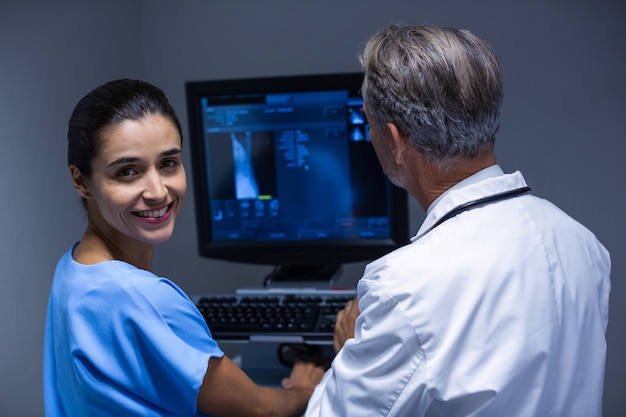 Médico y enfermera examinando rayos x en computadora