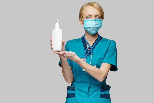 Médico enfermera con máscara protectora - sosteniendo spray desinfectante para manos o gel o jabón líquido