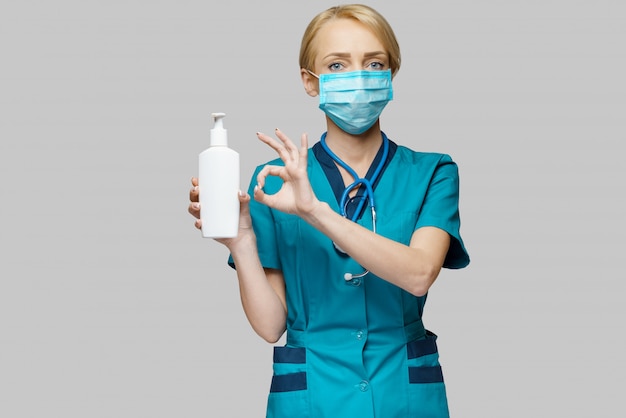 Médico enfermera con máscara protectora - sosteniendo spray desinfectante para manos o gel o jabón líquido