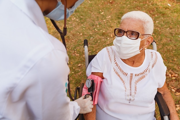 Médico enfermera midiendo la presión de la anciana