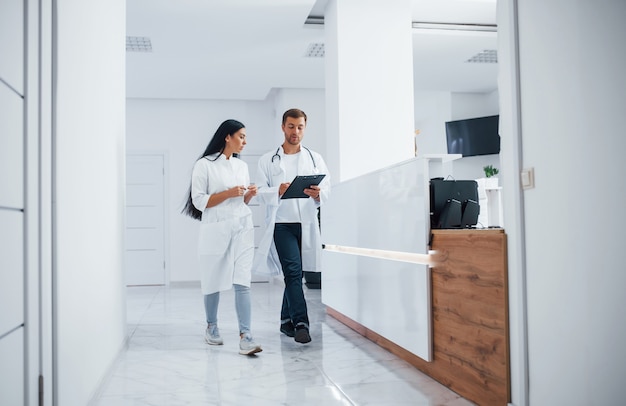 Foto médico y enfermera morena camina en el hospital y habla en el trabajo.