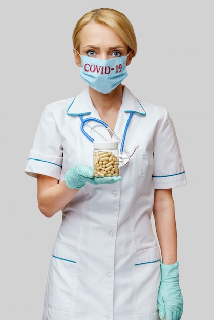 Médico, enfermera, mujer, llevando, máscara protectora, y, guantes de látex, tenencia, lata de píldoras