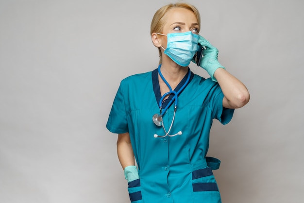 Médico enfermera mujer con máscara protectora y guantes de látex - hablando por teléfono