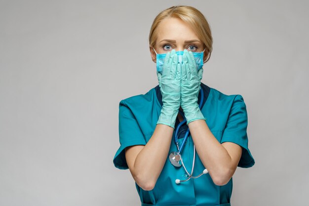 Médico enfermera mujer con máscara protectora y guantes de látex - rezando nad esperando gesto