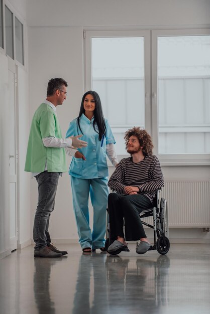 El médico, la enfermera y el paciente en silla de ruedas conversan en el pasillo moderno del hospital