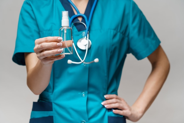 Foto médico enfermera usando una máscara protectora sosteniendo una botella de spray o gel desinfectante