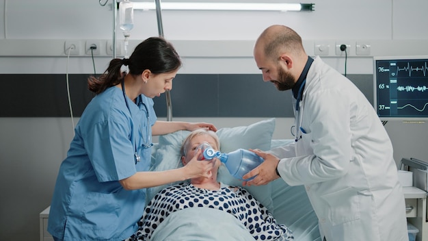 Médico y enfermera usando tubo de oxígeno y oxímetro en pacientes enfermos que respiran pesadamente en la cama. Equipo médico ayudando a mujeres mayores a curar problemas respiratorios con equipos y herramientas.