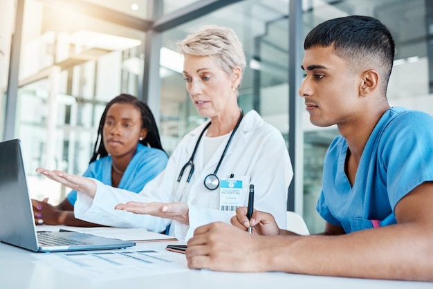 Médico ensinando estudantes de medicina no laptop em um escritório no hospital enquanto escreve notas Professor experiente com estetoscópio treinando profissionais de saúde Cirurgiões analisando resultados no computador