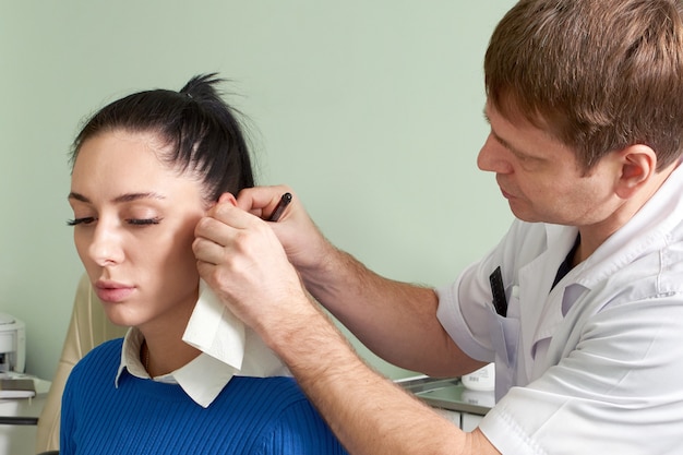 Foto médico ent atencioso fazendo exame de ouvido de uma linda mulher