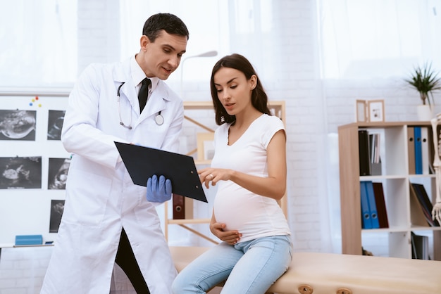 Foto médico escreve uma receita no papel para uma menina grávida.