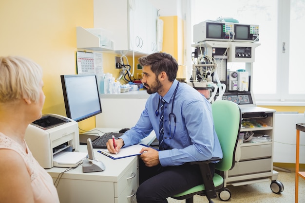 Médico escrevendo na área de transferência enquanto olha para o computador