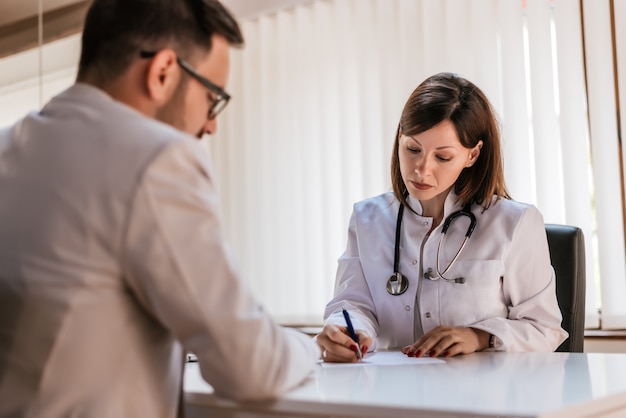 Médico escrevendo receita para o paciente