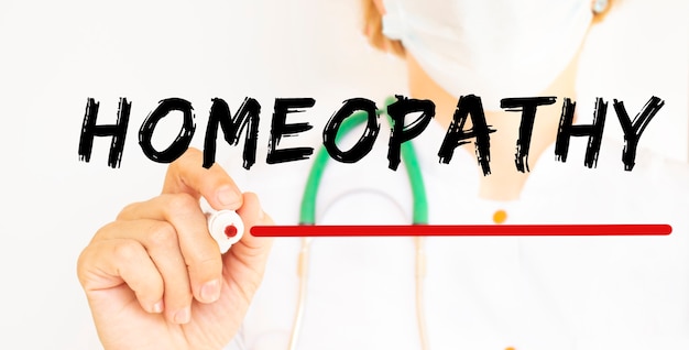 El médico escribe el texto HOMEOPATÍA con un marcador.