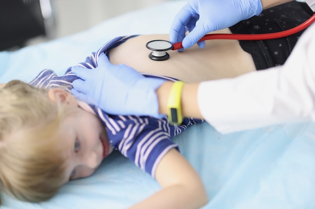 El médico escucha los pulmones de la niña con un estetoscopio. Examen por un pediatra. Atención médica para niños