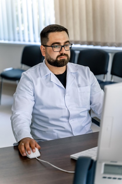 Médico esfrega trabalhando no computador. Sentado na cadeira no consultório médico.