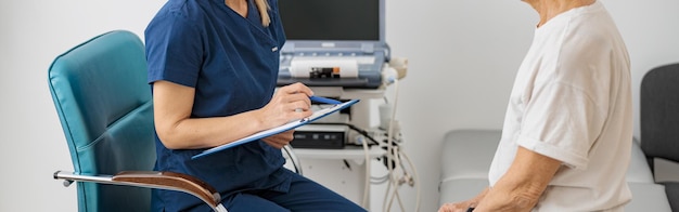 Médico especialista en ultrasonido toma notas en el portapapeles durante la cita del paciente en la clínica