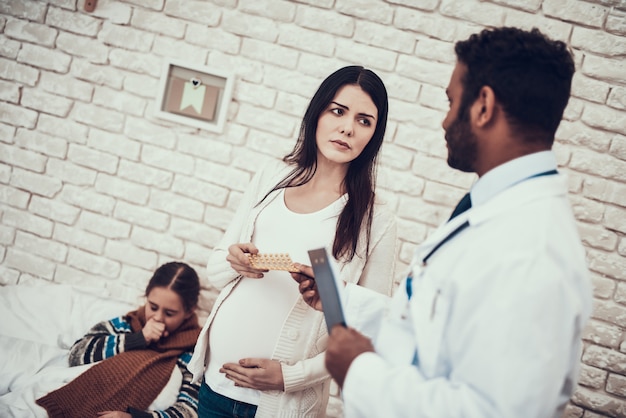 Médico está dando pílulas para jovem mãe grávida.