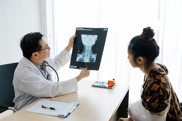 Médico está explicando sobre os resultados de raios-x do cérebro para uma paciente do sexo feminino em seu escritório em ho