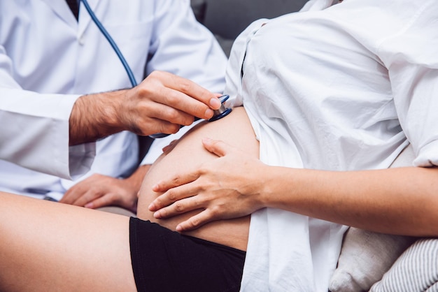 Foto médico está verificando mulher grávida com estetoscópio no conceito de saúde hospitalar