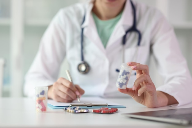 Foto el médico con estetoscopio prescribe medicamentos sentados a la mesa en la clínica. el terapeuta tiene plástico.