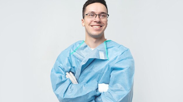 Médico estudante masculino com óculos mostra sorrindo de uniforme