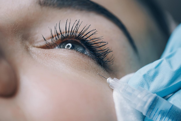 El médico del estudio de belleza realiza inyecciones cosméticas en la piel de la cara de un paciente joven.