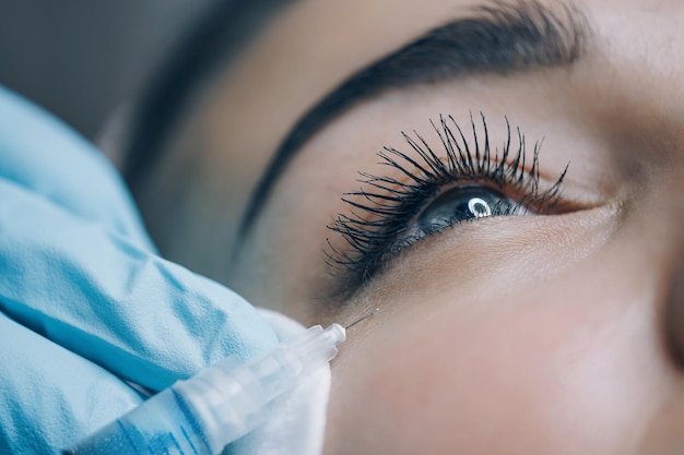 El médico del estudio de belleza realiza inyecciones cosméticas en la piel de la cara de un paciente joven.