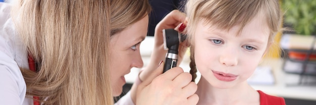 Médico examina ouvido com um otoscópio para teste de audição de menina no conceito de crianças