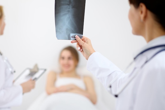 El médico examina una radiografía junto a un alegre paciente sonriente en el hospital.