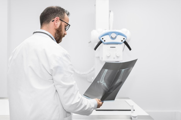 El médico examina una radiografía de película de un paciente en la sala de radiología