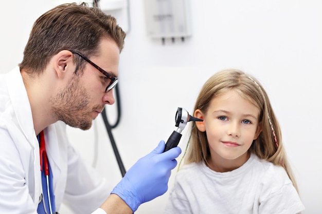 Médico examinando a orelha de uma menina com um otoscópio